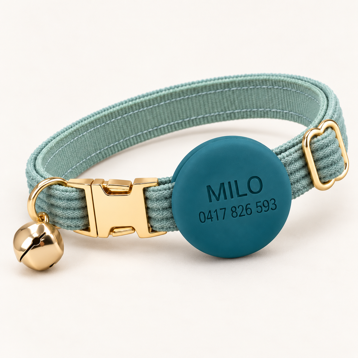 Mist | Corduroy cat collar with matching silicone AirTag holder, gold non-breakaway buckle and removable bell, soft natural studio hero.