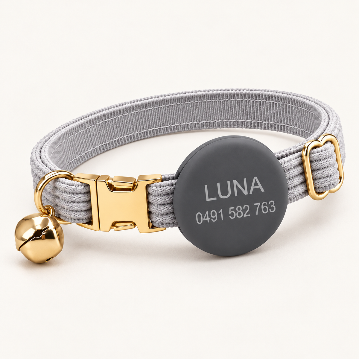 Pebble | Corduroy cat collar with matching silicone AirTag holder, gold non-breakaway buckle and removable bell, soft natural studio hero.
